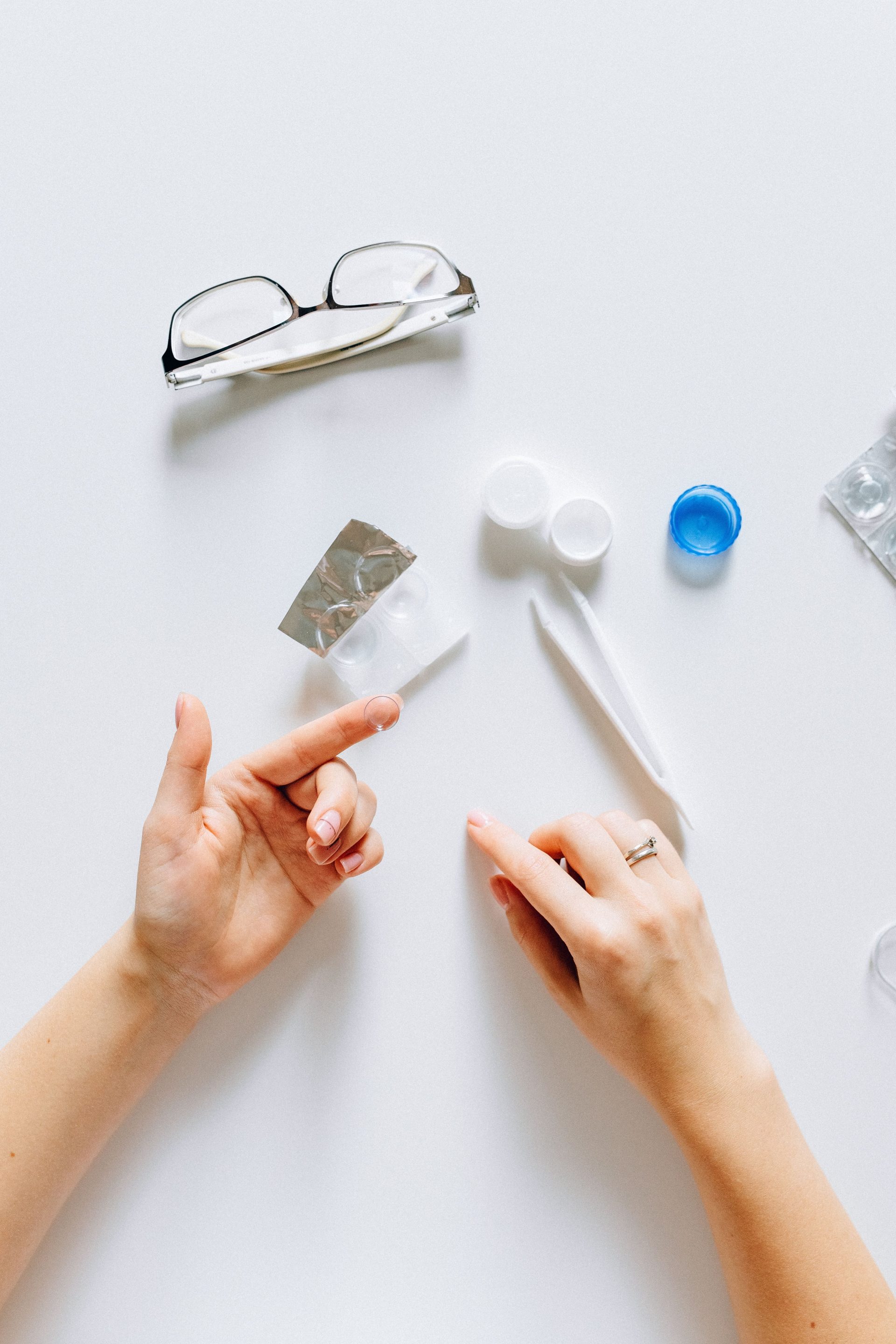 Vue à plat d'accessoires pour lentilles de contact, de lunettes et de mains, idéale pour des thèmes liés aux soins de la vue.