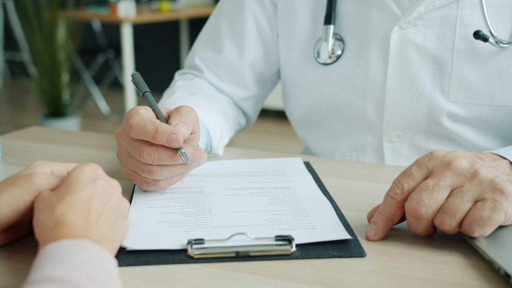 Médecin écrivant sur le dossier d'un patient